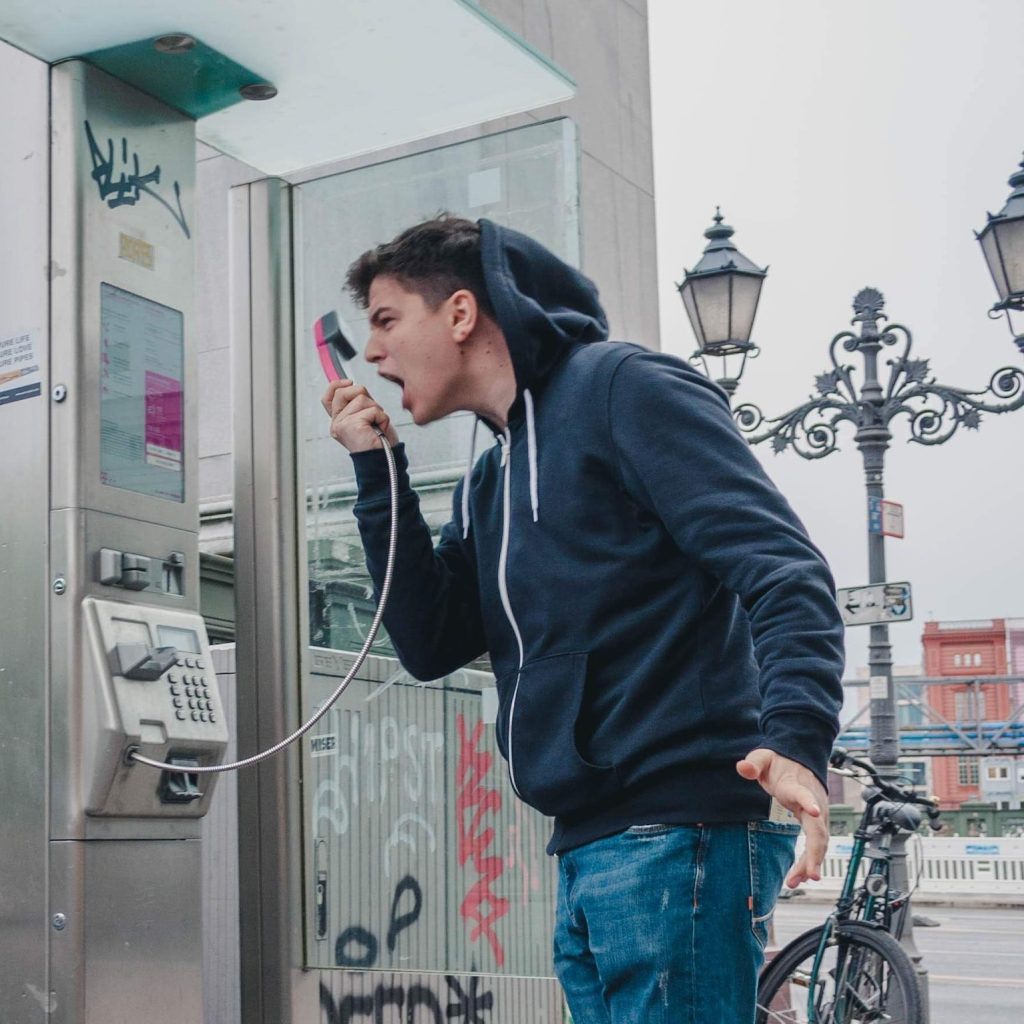 A person shouting into a public telephone